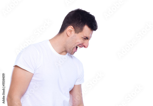 Shouting out loud. Side view of furious young man shouting and keeping eyes closed while standing isolated on white © HBS