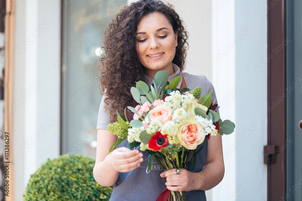Woman florist with flower bouquet standing in front of shop Woman florist with flower bouquet standing in front of shop
