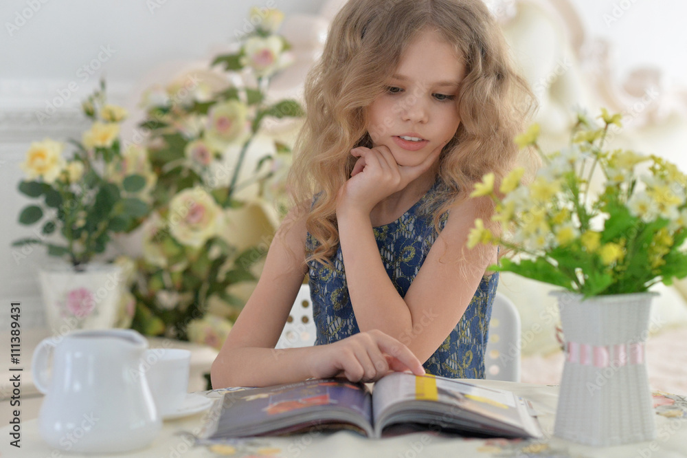 Young little girl reading a magazine