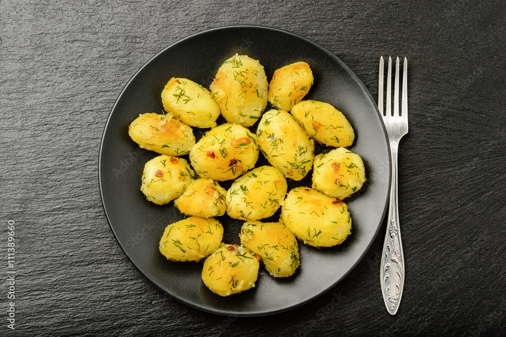 Roasted young potatoes with garlic and dill on black background. Roasted young potatoes with garlic and dill on black background.