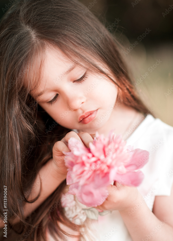 Cute baby girl 4-5 year old holding pink flower outdoors closeup Cute baby girl 4-5 year old holding pink flower outdoors closeup
