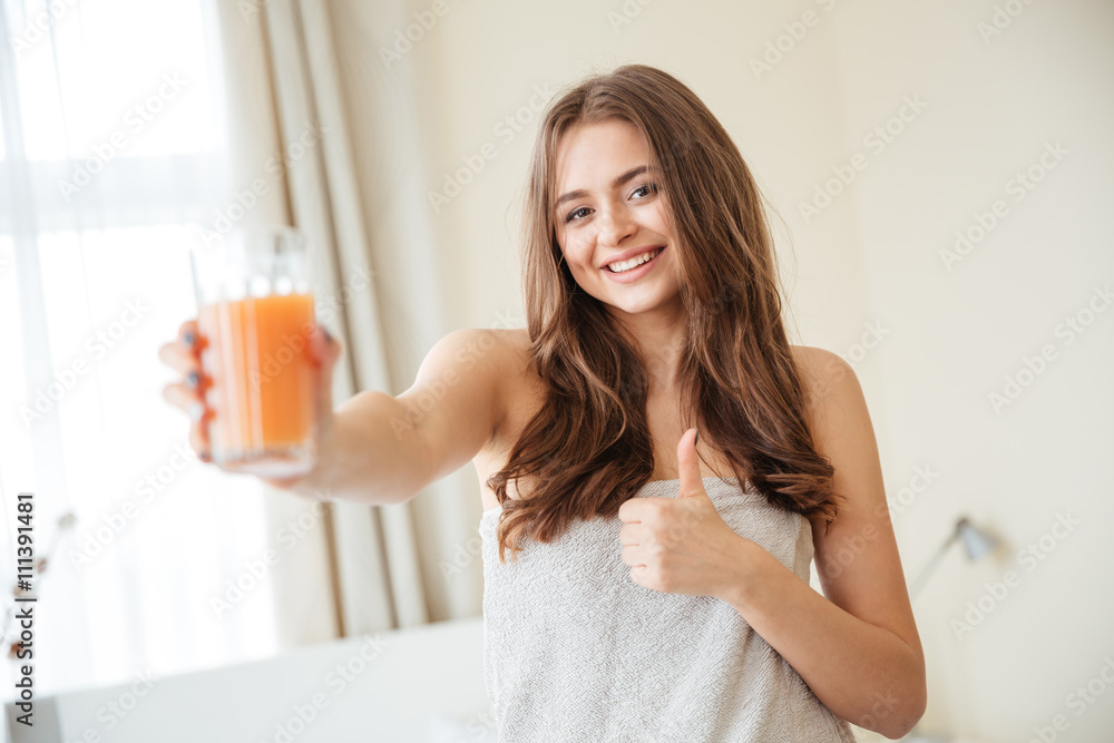 Woman holding glass with orange juice and showing thumb up Woman holding glass with orange juice and showing thumb up