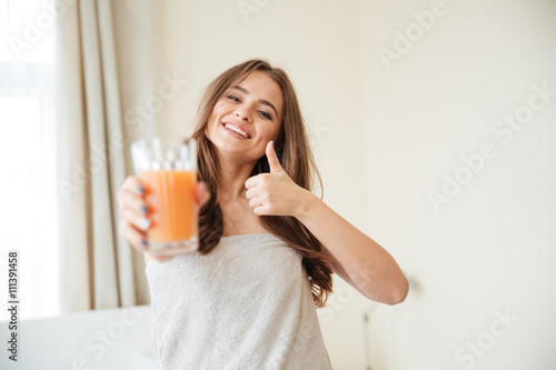 Woman holding orange juice and showing thumb up