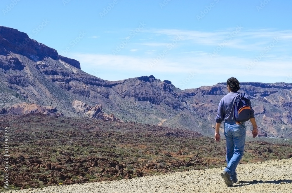 Man with his backpack walking on volcanic mountains of Tenerife. Concept for travel o tourism