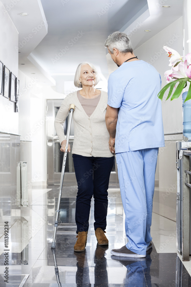 Physiotherapist Helping Senior Patient With Crutches Physiotherapist Helping Senior Patient With Crutches