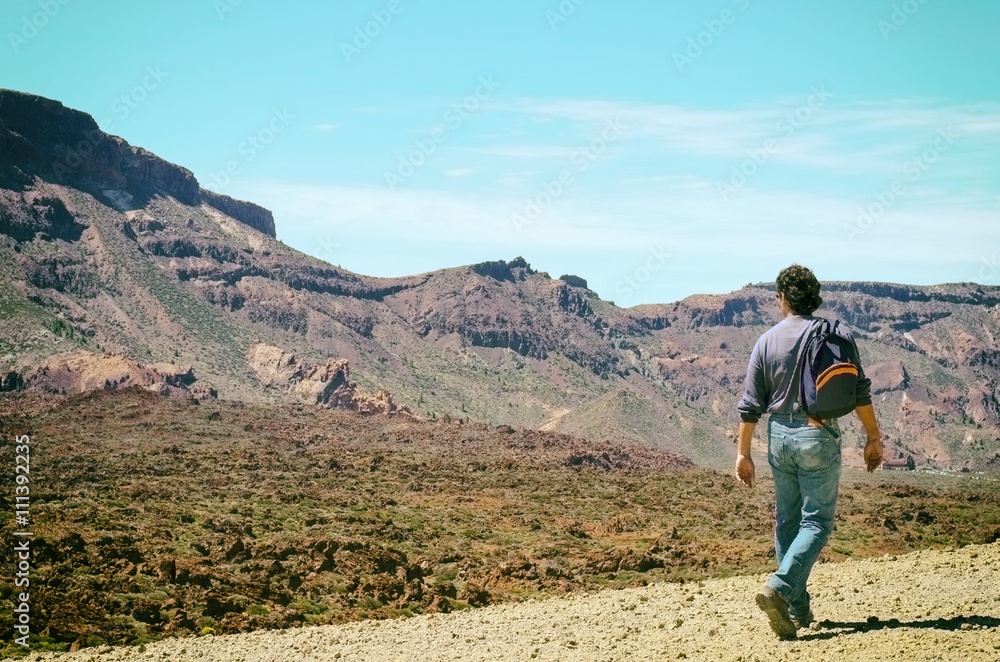 Man with his backpack walking on volcanic mountains of Tenerife. Concept for travel o tourism.Vintage style Man with his backpack walking on volcanic mountains of Tenerife. Concept for travel o tourism.Vintage style