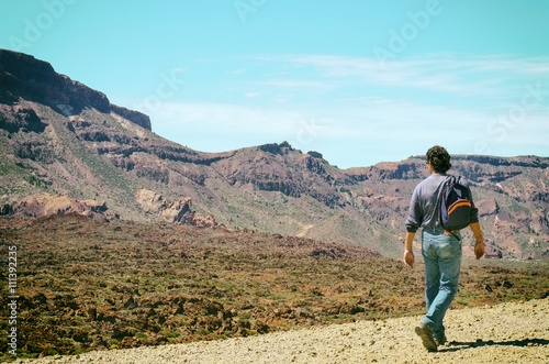Man with his backpack walking on volcanic mountains of Tenerife. Concept for travel o tourism.Vintage style