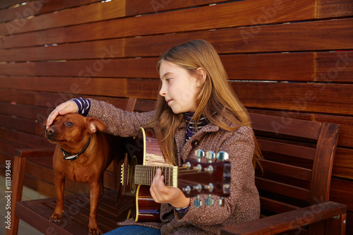 kid girl playing guitar with dog and winter beret