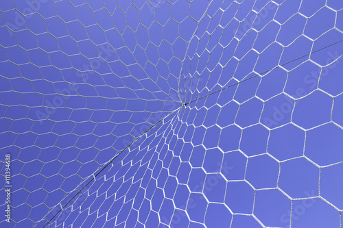 Closeup of white soccer net over blue sky