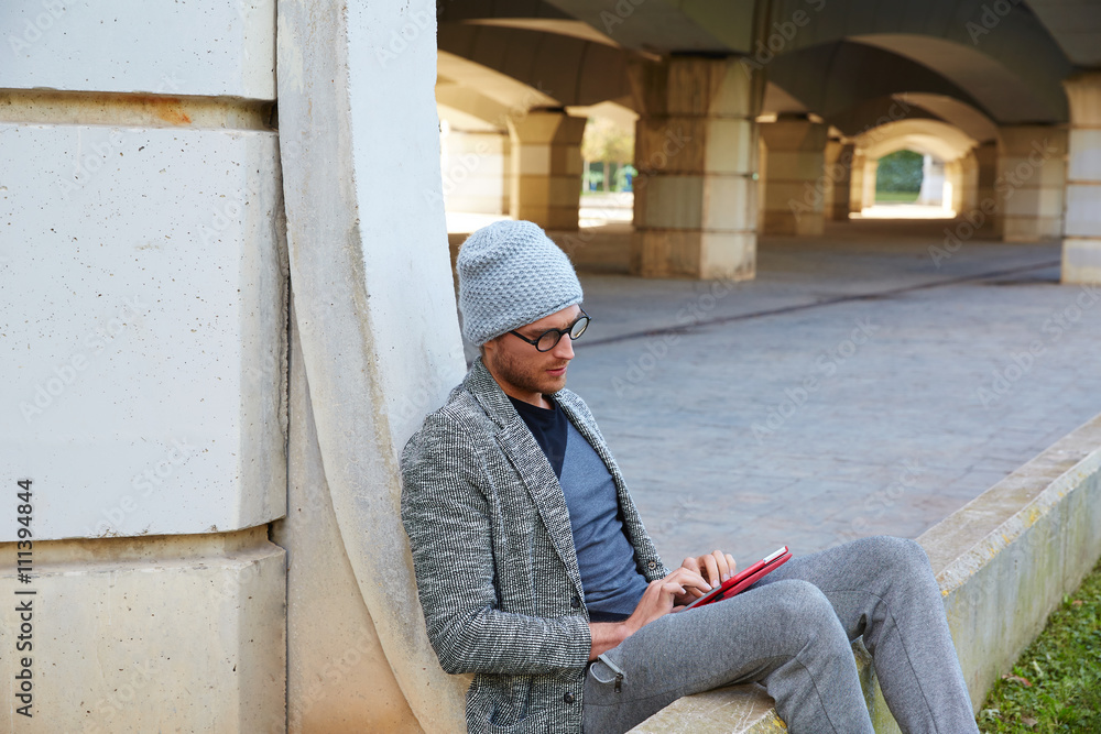 Modern young man with tablet pc under a bridge