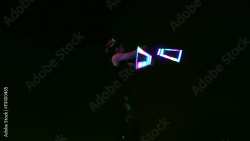 Juggler showing tricks with light balls in the whole dark. photo