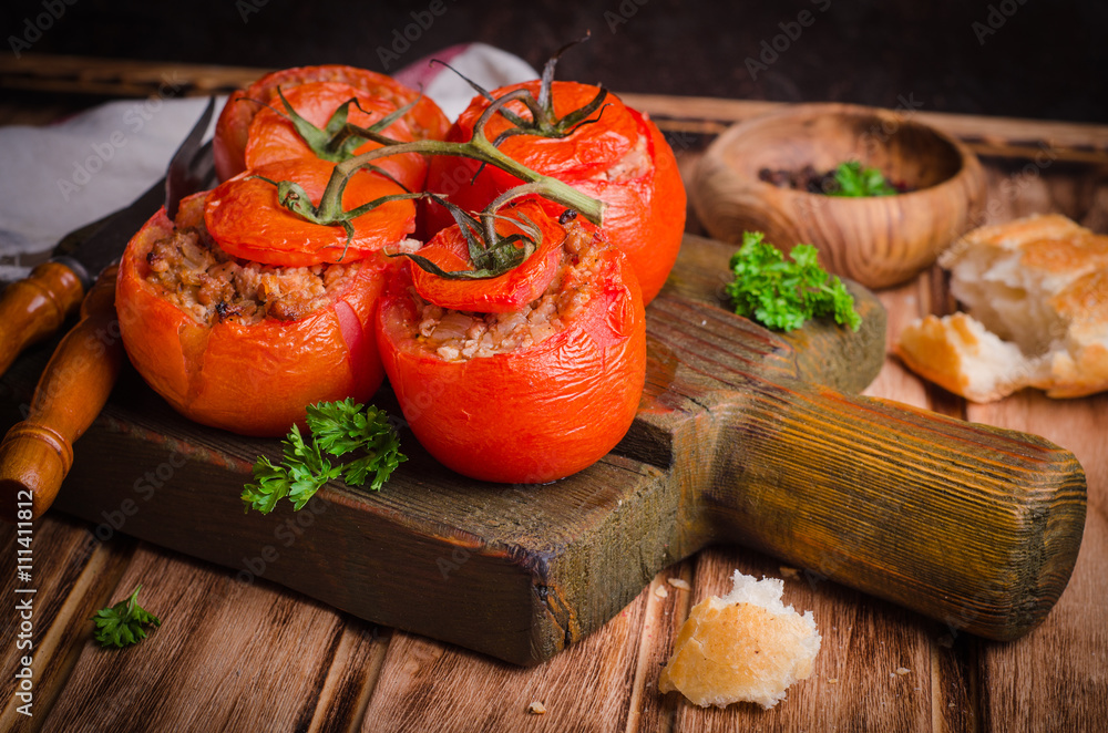 Baked stuffed chicken tomatoes served on cutting board on wooden background. Selective focus Baked stuffed chicken tomatoes served on cutting board on wooden background. Selective focus