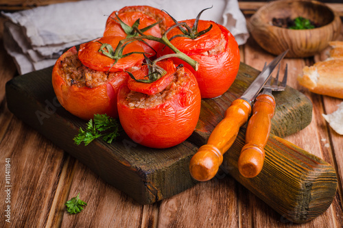 Fotografia Baked stuffed chicken tomatoes served on cutting board  on wooden background