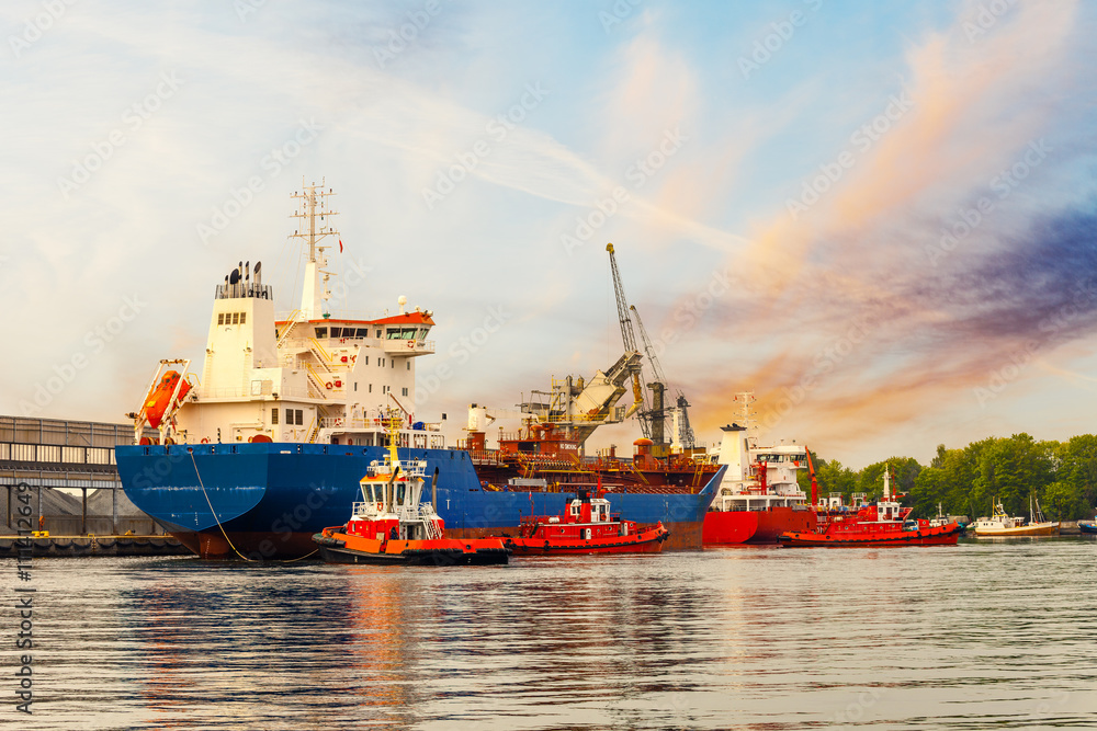 Tugboats maneuver a cargo ship in port of Gdansk, Poland.