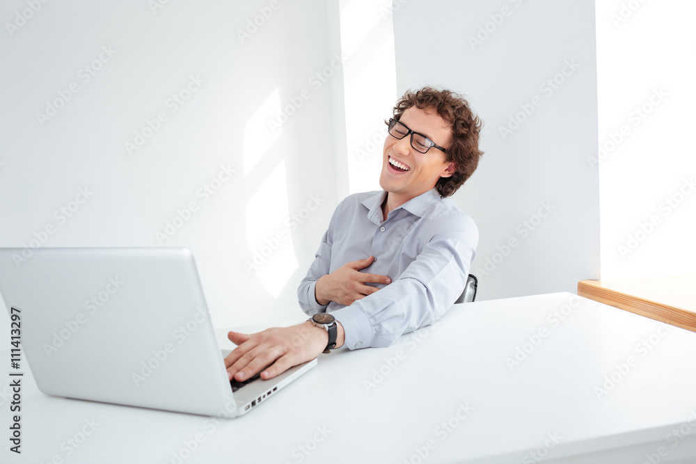 Laughing businessman sitting at his workplace Laughing businessman sitting at his workplace