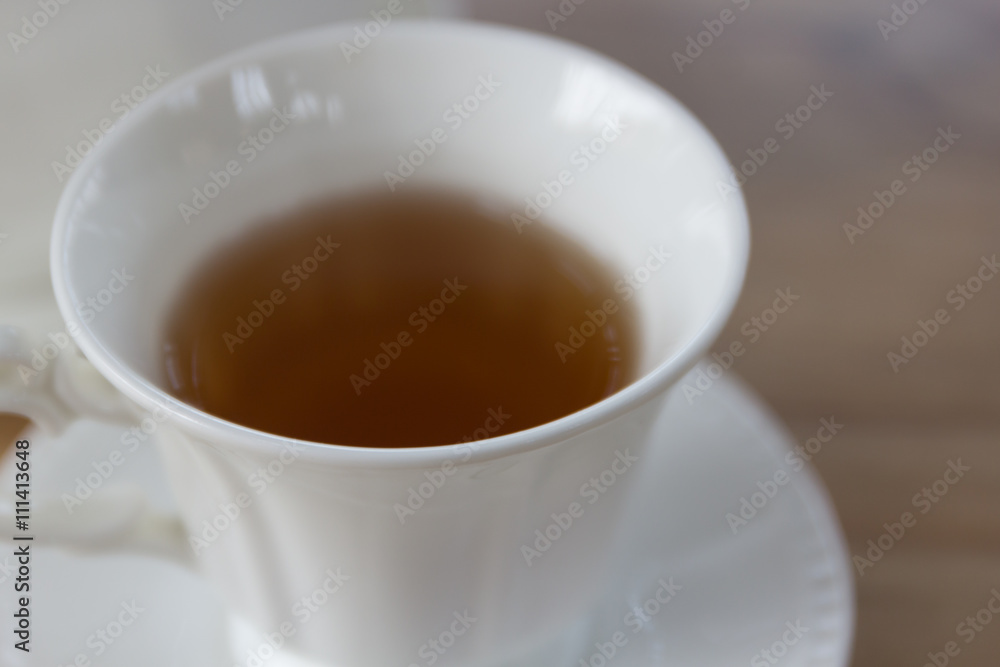 Hot black tea in white cup set on wooden table Hot black tea in white cup set on wooden table