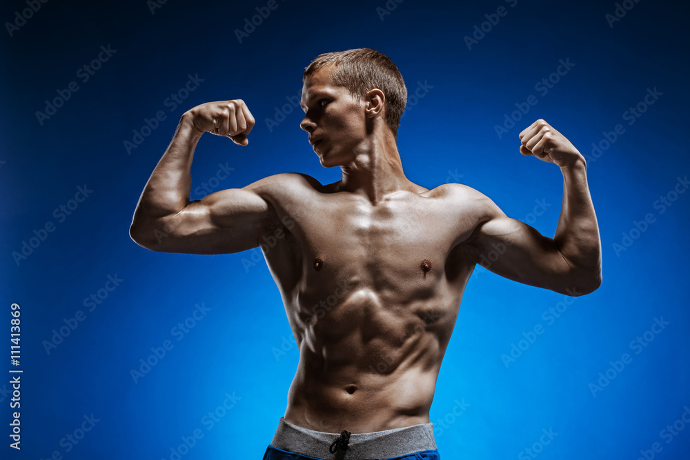 Obraz premium Fit young man with beautiful torso on blue background