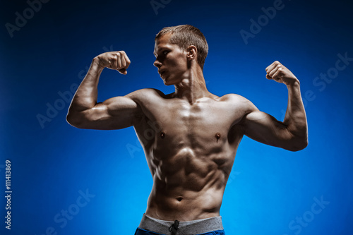 Fit young man with beautiful torso on blue background