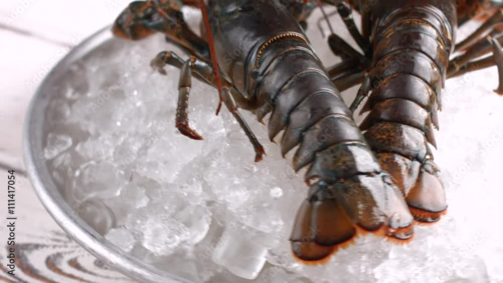 Raw lobsters with tied claws. Lobsters on plate with ice. Table in restaurant kitchen. Big claws and strong shell. Raw lobsters with tied claws. Lobsters on plate with ice. Table in restaurant kitchen. Big claws and strong shell.