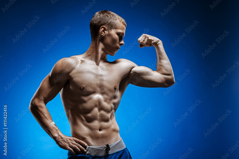 Fototapeta premium Fit young man with beautiful torso on blue background