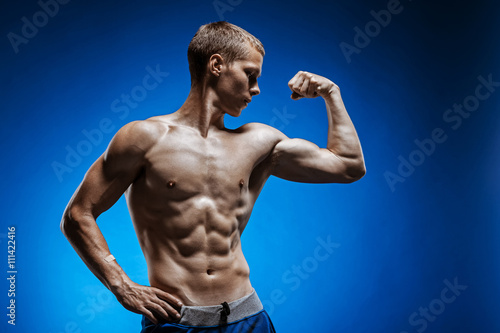 Fit young man with beautiful torso on blue background