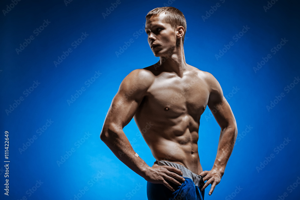 Fototapeta premium Fit young man with beautiful torso on blue background
