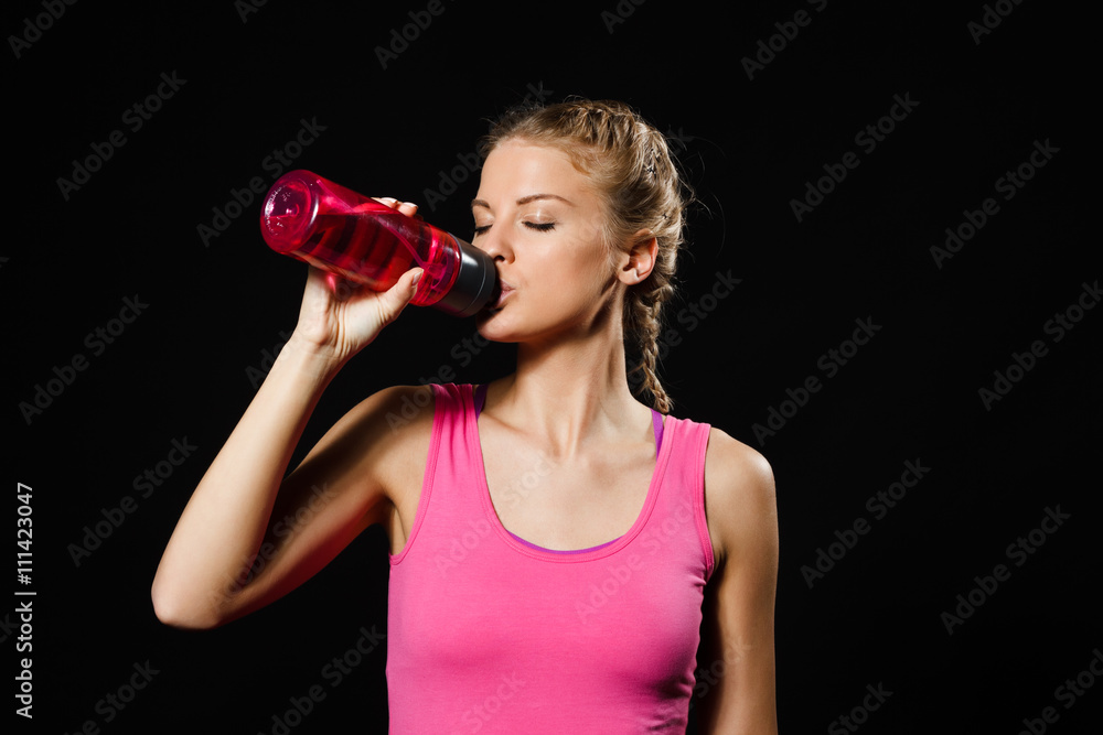 Beautiful blonde woman is drinking water after exercise. 