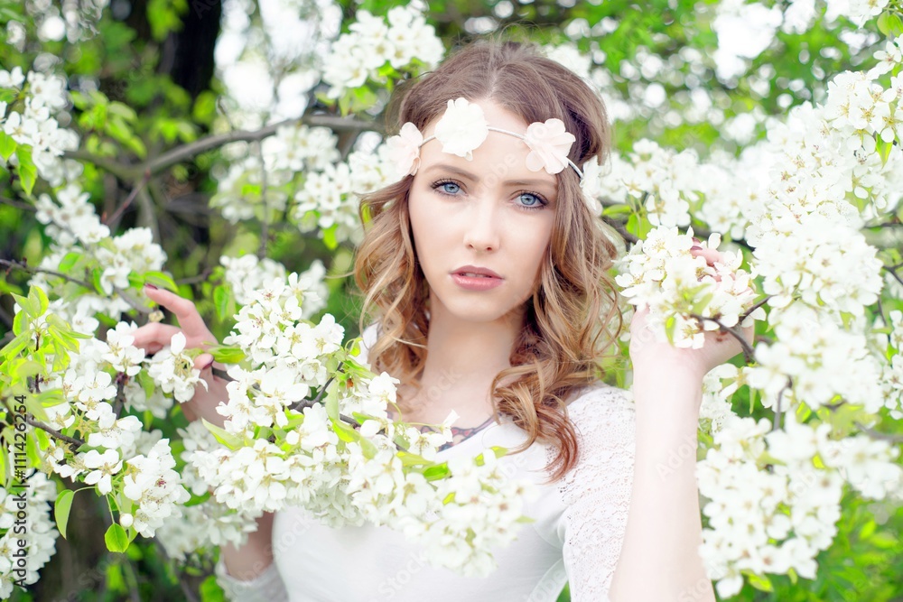 Spring / pretty woman with flower hair band in front of a blossoming apple tree Spring / pretty woman with flower hair band in front of a blossoming apple tree