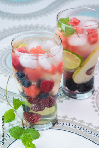 Glasses of fruit and berries, mint infused water with ice.