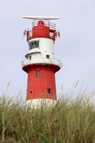 red and white stripped lighthouse with marram grass in the foreground