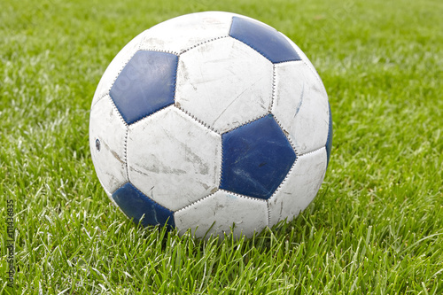 Close up picture of used soccer ball on grass.