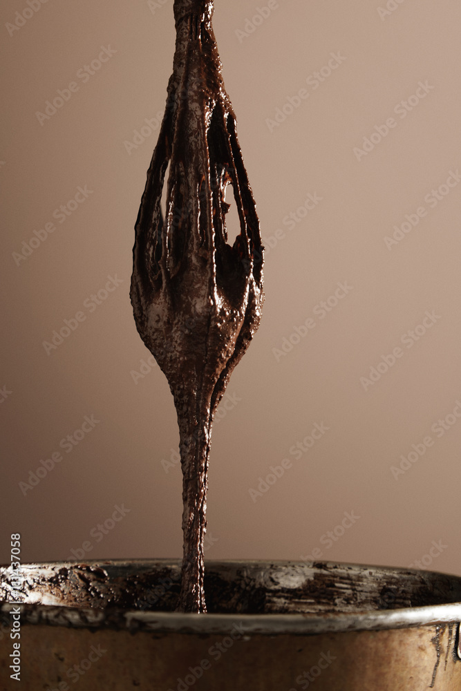 Close up big industrial whisk with melted chocolate isolated on background, professional baking in artisan confectionery process