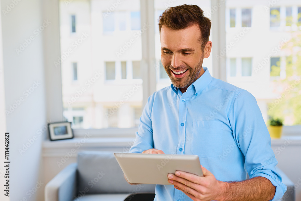 Happy man using digital tablet at home Happy man using digital tablet at home