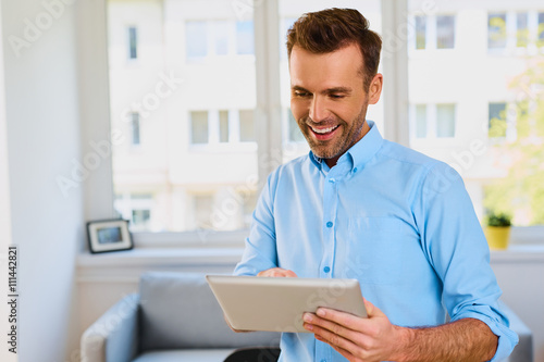 Happy man using digital tablet at home