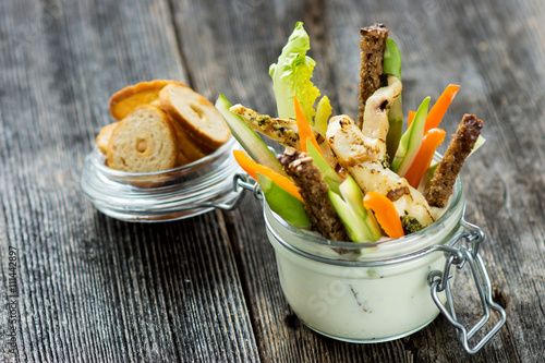 Grilled chicken wings with creamy sauce for dipping with a glass filled with sliced fresh vegetable  photo