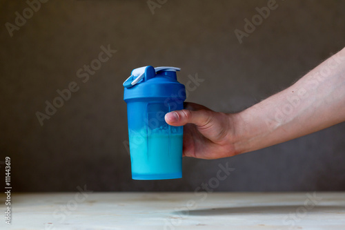 male hand, holding a shaker Cup with protein
