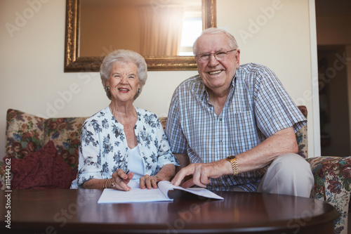Obraz na płótnie Smiling retired couple looking over documents