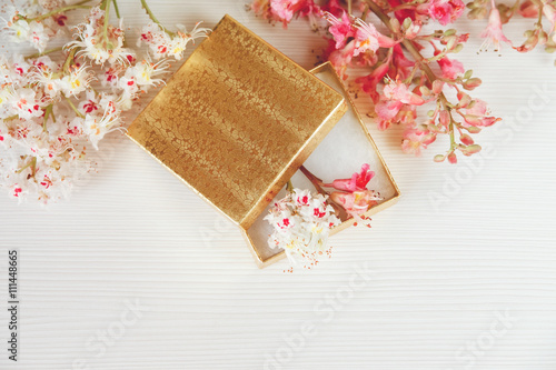 There Gold Open Box with White and Pink Branches of Chestnut Tree are on White Table,Top View,Toned