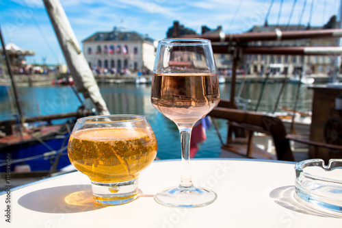 Glass with tasty apple cider and rose vine in old French fisherm photo