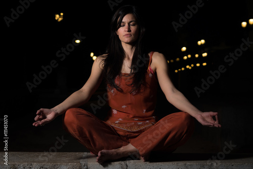 Beautiful woman practicing meditation at night