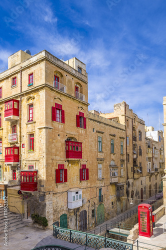 Malta, Valletta - Streetview with traditional red balconies and windows and red telephone box