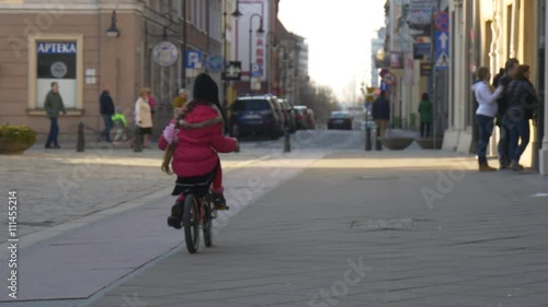 Wallpaper Mural Little Girl is Riding the Bike Fast by City Square in Opole Poland Child is Riding Among Crowd of People Walking by a Street in Sunny Day Springtime Torontodigital.ca
