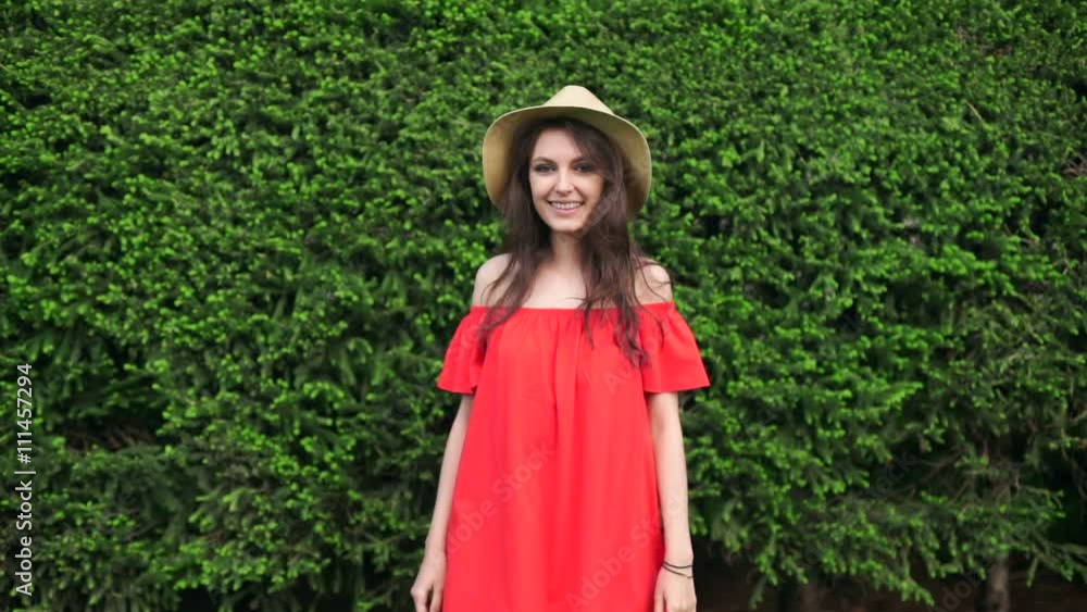 SLOW MOTION. Beautiful happy model standing playful in red dress on nature SLOW MOTION. Beautiful happy model standing playful in red dress on nature