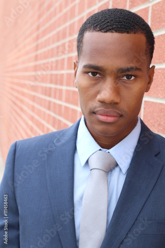 Confident and handsome. Confident young African man in formalwear looking at camera while standing against gorgeous red brick wall background