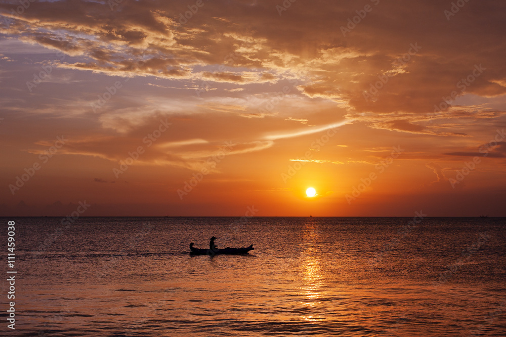 Man in boat witnessing a magical golden sunset in Bali, Indonesia  