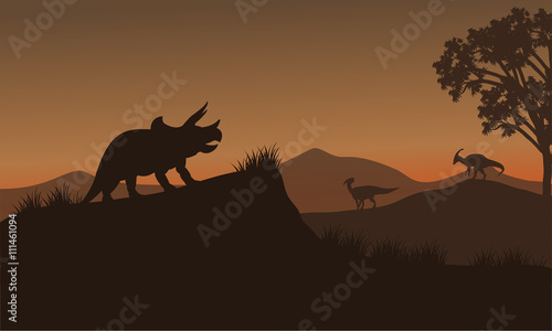 Triceratops and Eoraptor silhouette in hills