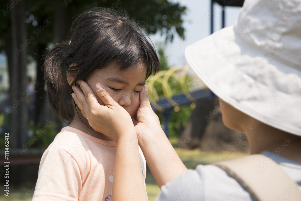 子供の顔に日焼け止めを塗る母親