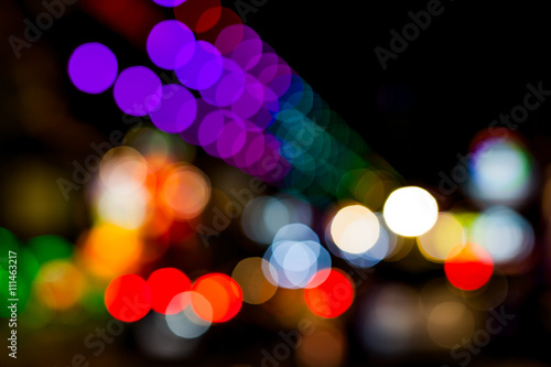 Bokeh of lights on buildings along the sidewalks .
