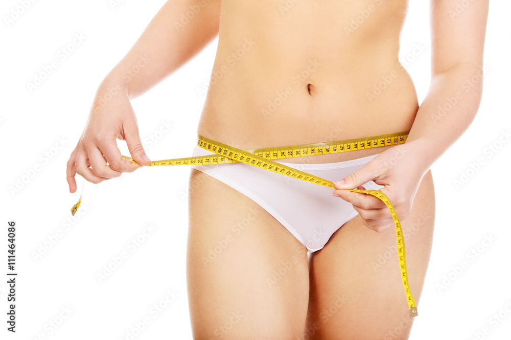 Beautiful slim woman measuring her hips
