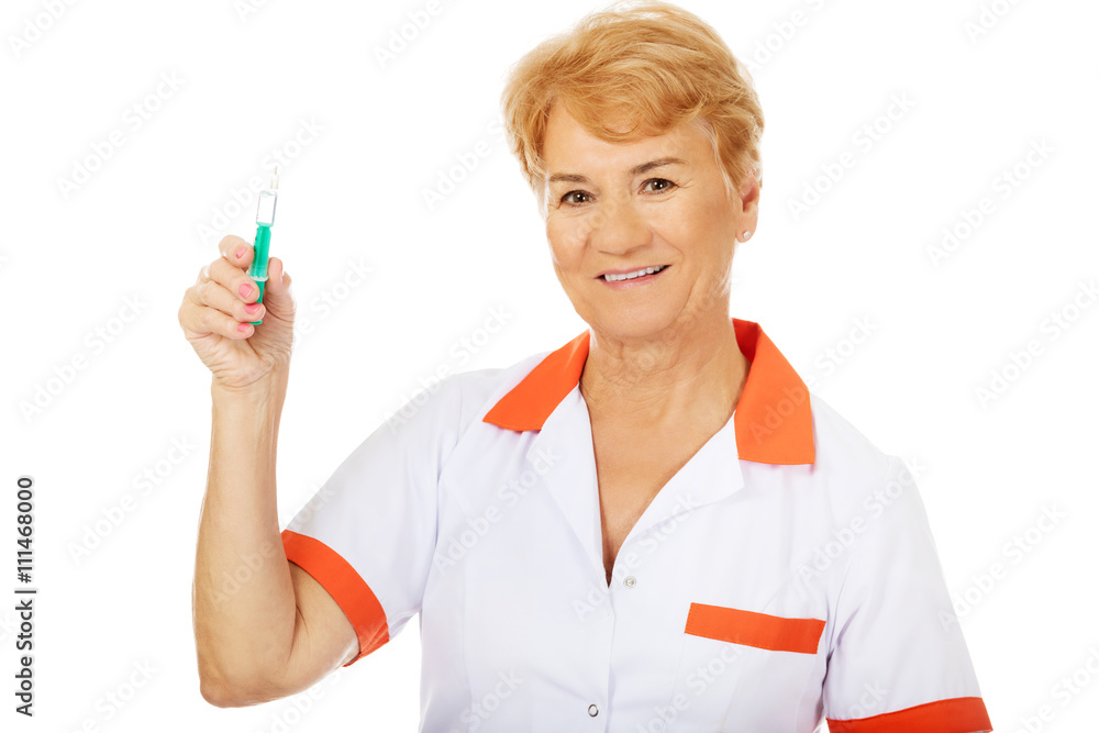 Smile elderly female doctor or nurse holds syringe Smile elderly female doctor or nurse holds syringe